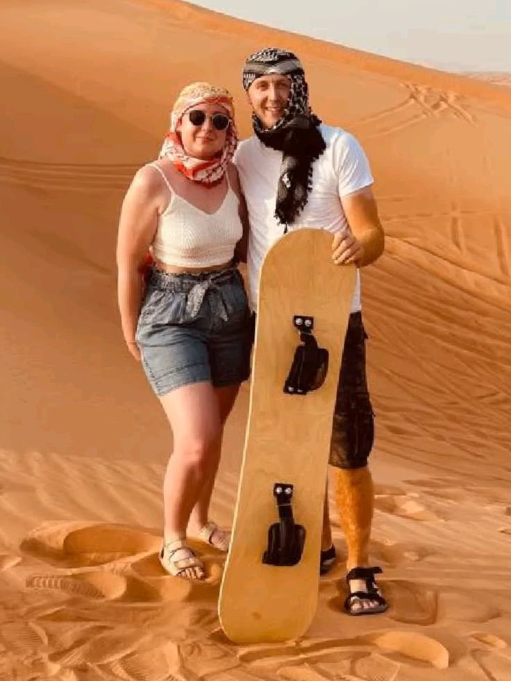 Couple on a short camel ride across the dunes in late-afternoon light