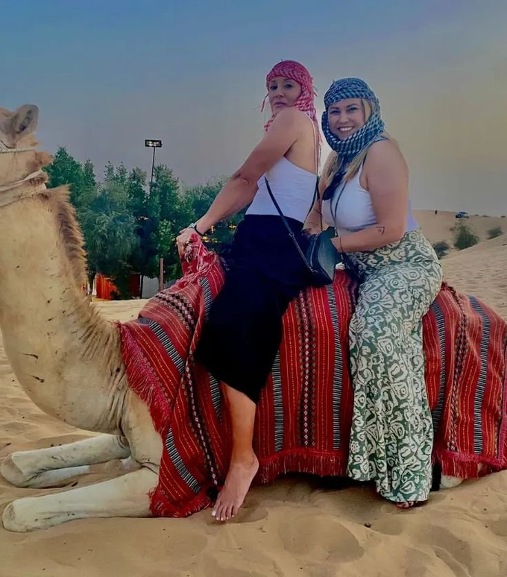 Friends sharing a camel ride on the dunes