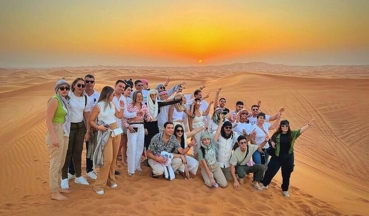 Small group posing on a dune ridge at sunset
